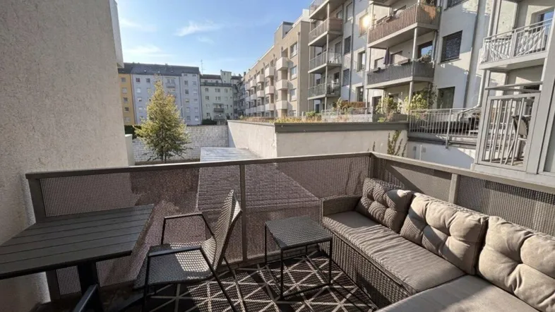 Gemütlicher Balkon mit bequemen Outdoor-Möbeln und Blick auf die umliegenden Wohngebäude.