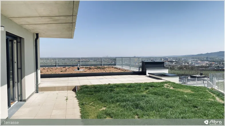 Große Dachterrasse mit Fliesen und Grünfläche bietet einen weiten Blick über die Umgebung.