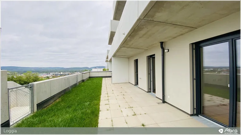 Geräumige Loggia mit Fliesenboden und Grünfläche, bietet einen weiten Ausblick über die Landschaft.