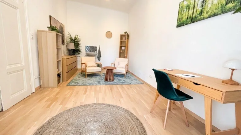 Geräumiger Büroraum mit hellem Holzboden, Schreibtisch, Sitzgelegenheiten und einem dekorativen Wandbild.