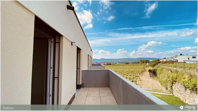 Geräumiger Balkon mit Fliesenboden und weitem Blick über Weinberge und die umliegende Landschaft.