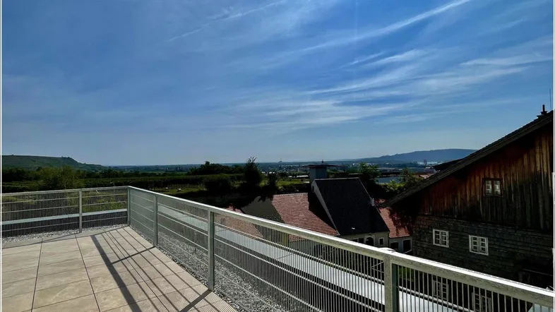 Große Dachterrasse mit Fliesenboden und weitem Blick über die Landschaft und die Stadt.