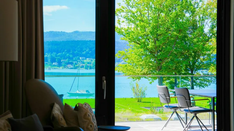 Gemütlicher Innenbereich mit Sessel und direktem Zugang zur Terrasse mit Seeblick.