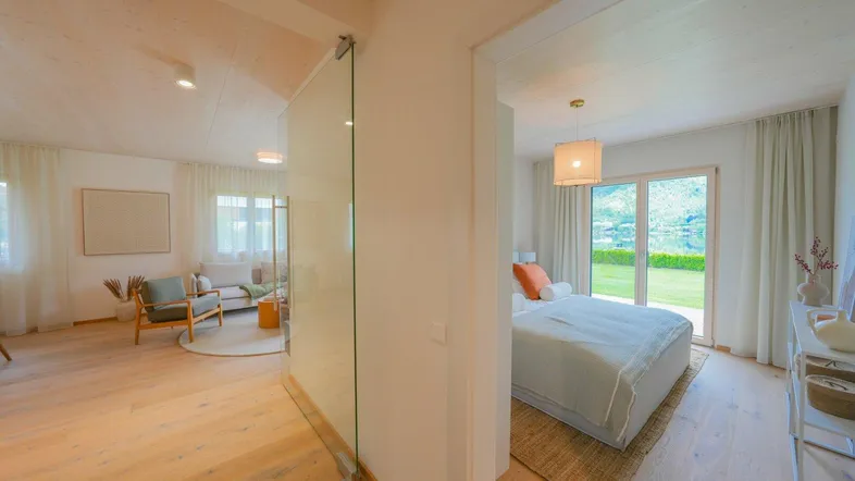 Übergangsbereich mit Glaswand zwischen Wohnzimmer und Schlafzimmer mit Gartenblick.