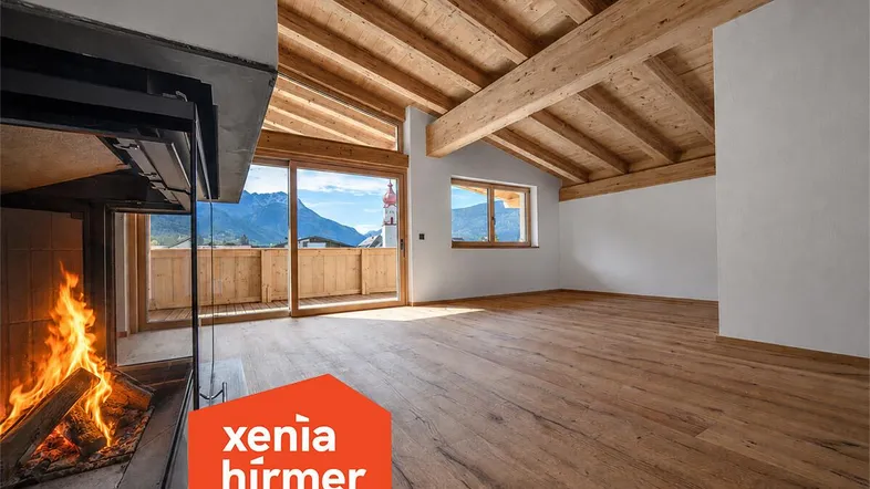 Geräumiges Wohnzimmer mit Holzbalkendecke, Kamin und Zugang zu einem Balkon mit Bergblick.