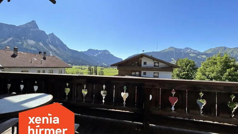 Geräumiger Balkon mit Holzboden und traditionellem Geländer, bietet einen weiten Blick auf die umliegende Berglandschaft.