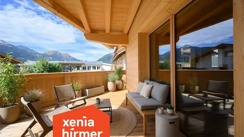 Möblierter Holzbalkon mit Bergblick und gemütlicher Sitzecke unter einer Holzdecke.