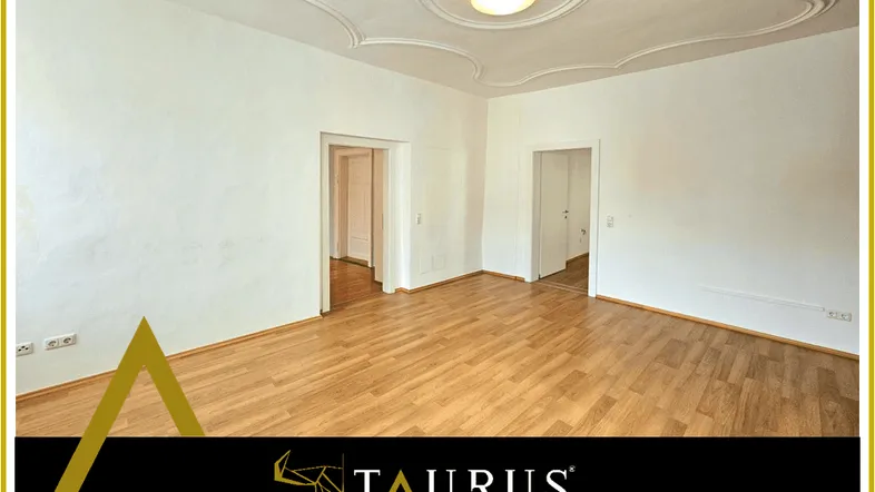 Helles Zimmer mit Holzboden und einer dekorativen Stuckdecke, bereit zur individuellen Gestaltung.