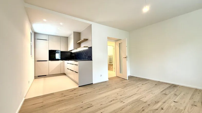 Heller offener Wohnbereich mit moderner Küche und Holzboden, ideal für geselliges Beisammensein.