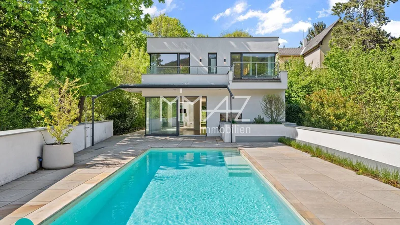 Modernes Haus mit Swimmingpool und Terrasse, umgeben von viel Grün und Bäumen.