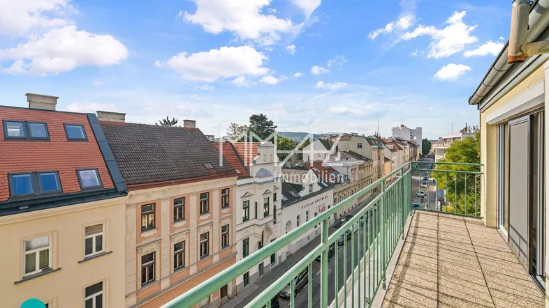 Geräumiger Balkon mit Blick auf die Stadt und die umliegenden Gebäude unter blauem Himmel.