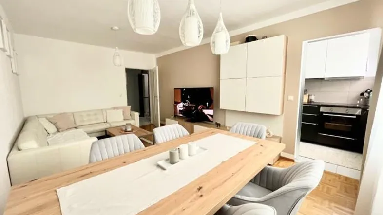 Heller Wohn- und Essbereich mit Holztisch, bequemer Couch und Zugang zur Küche.