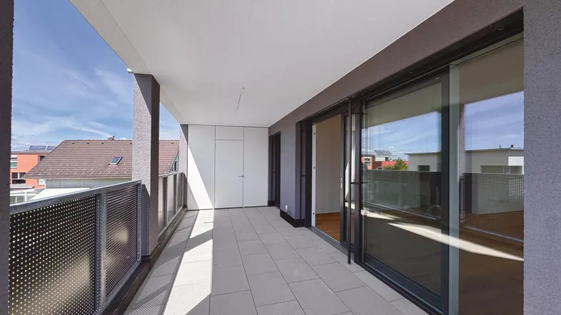 Geräumiger Balkon mit Fliesenboden und Schiebetüren, der viel Tageslicht in die Innenräume lässt.