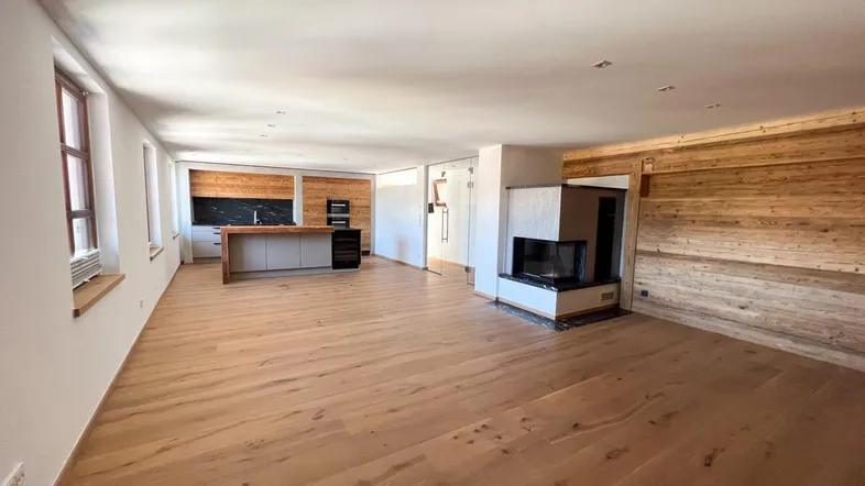 Geräumiger offener Wohn- und Essbereich mit Holzboden, moderner Küche und integriertem Kamin.