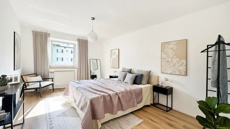 Helles Schlafzimmer mit modernem Interieur, Laminatboden und Fenster mit Blick nach draußen.