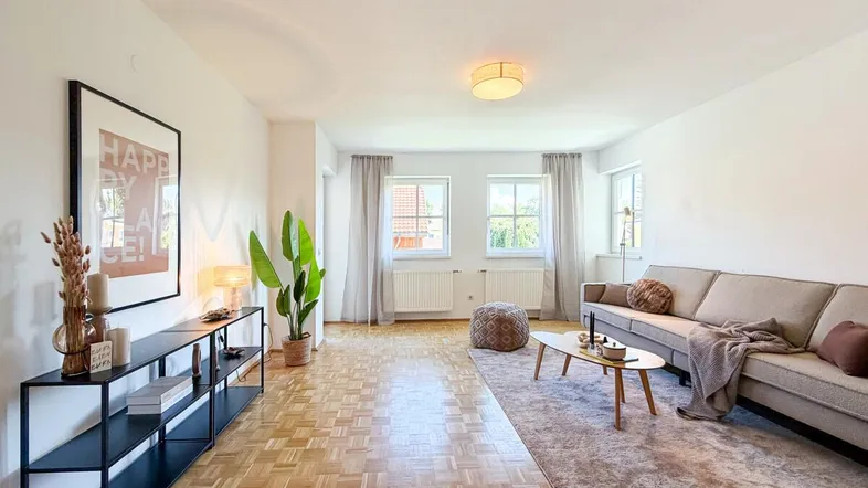 Helles und modern eingerichtetes Wohnzimmer mit Parkettboden, bequemer Couch und großen Fenstern.