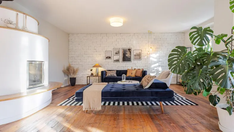 Helles Wohnzimmer mit Holzboden, modernem Kamin und einer Ziegelwand als Akzent.