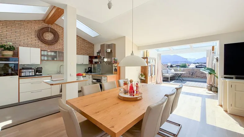 Heller offener Wohn- und Essbereich mit moderner Küche, Holzboden und Zugang zur Dachterrasse.