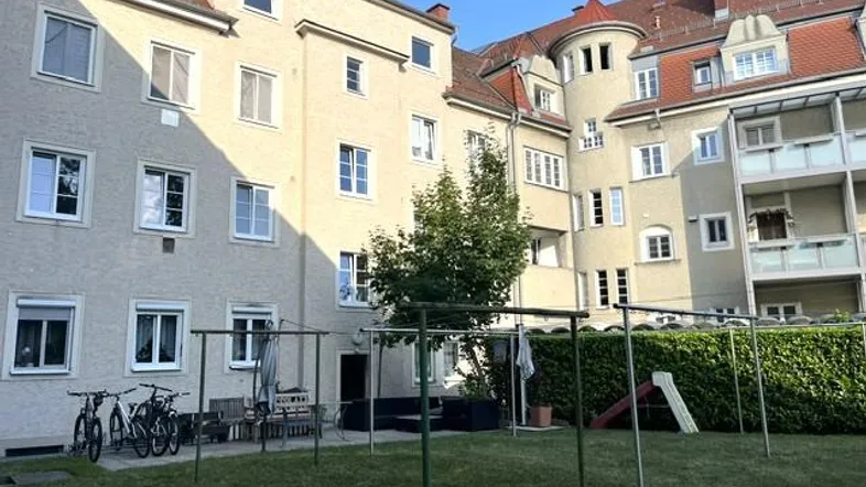Blick auf den gemeinschaftlichen Innenhof des Wohngebäudes mit Grünfläche und Spielbereich.