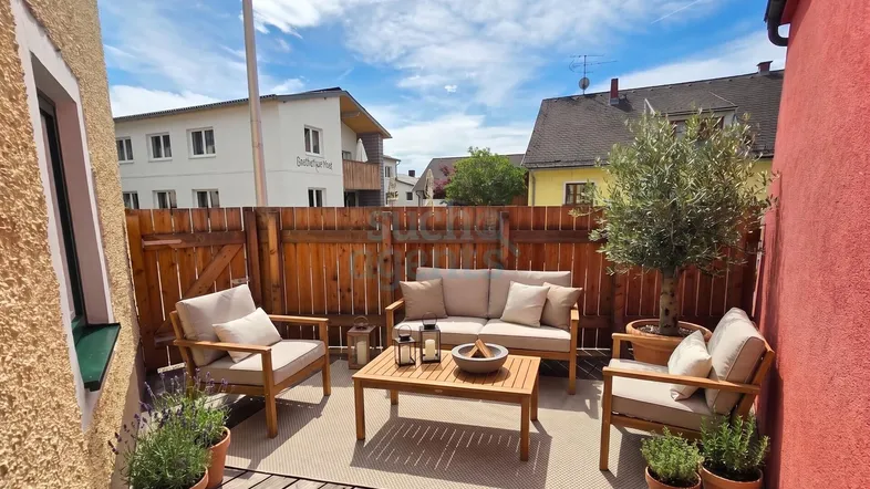 Gemütliche Terrasse mit Holzboden, Sitzmöbeln und Pflanzen, ideal zum Entspannen im Freien.