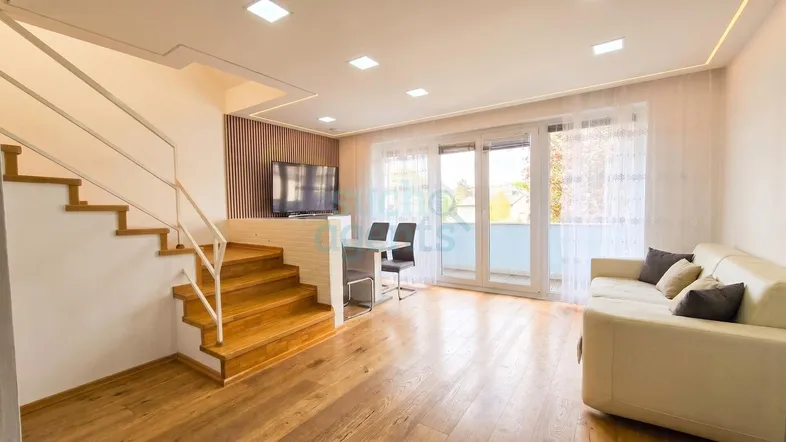 Heller offener Wohn- und Essbereich mit Holztreppe, Parkettboden und Zugang zum Balkon.
