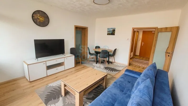 Geräumiges Wohn-Esszimmer mit bequemer Couch, Esstisch und Zugang zu weiteren Räumen.