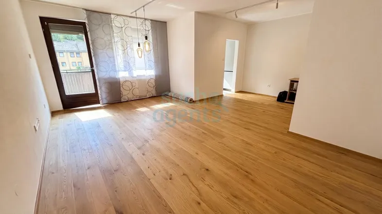 Heller Wohnbereich mit neuem Parkettboden, Zugang zum Balkon und viel Tageslicht.