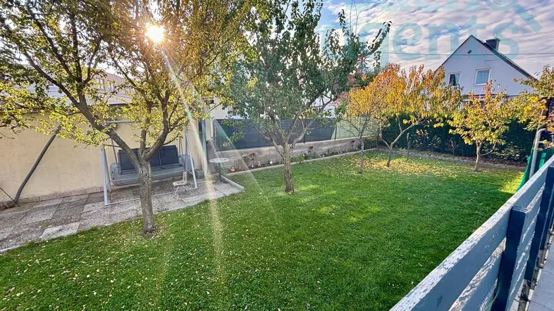 Gepflegter Garten mit Rasenfläche, Obstbäumen und einer Schaukel, ideal zum Entspannen im Freien.
