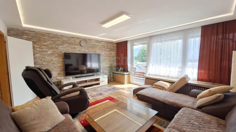 Helles Wohnzimmer mit Steinwand, Holzboden und Zugang zum Balkon, ausgestattet mit modernen Möbeln.