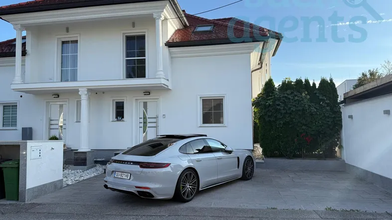 Moderne weiße Doppelhaushälfte mit gepflasterter Einfahrt und Satteldach.