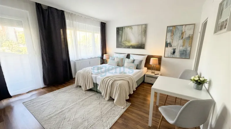 Helles Schlafzimmer mit Doppelbett, Holzboden und einem kleinen Essbereich am Fenster.