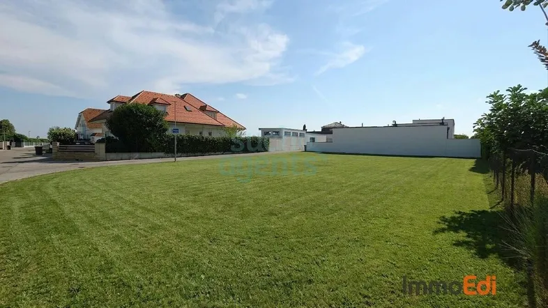 Großes, gepflegtes Grundstück mit Rasenfläche und Blick auf umliegende Häuser unter blauem Himmel.