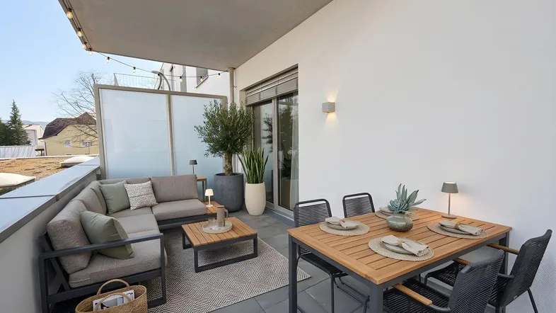 Geräumige Terrasse mit modernen Gartenmöbeln, Essbereich und gemütlicher Lounge-Ecke für entspannte Stunden im Freien.