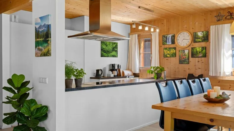 Offene Küche mit Holzbalkendecke, moderner Dunstabzugshaube und Essbereich.