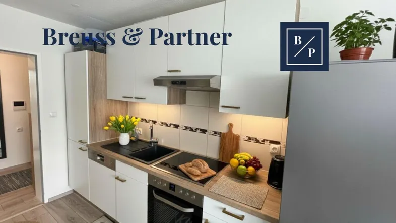Moderne Einbauküche mit weißen Schränken, Holzdetails und gelben Tulpen auf der Arbeitsplatte.