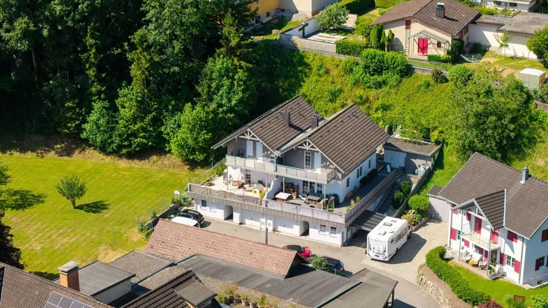 Luftaufnahme des Hauses mit umliegender grüner Landschaft und Nachbargebäuden.