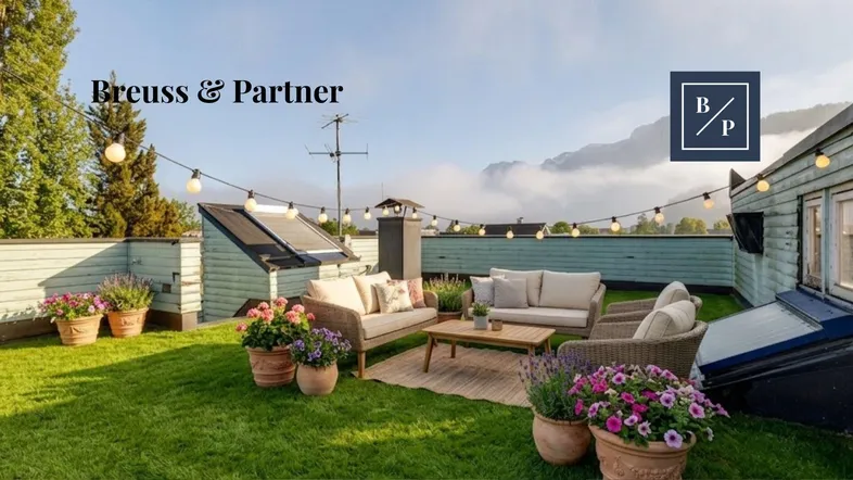 Gemütliche Dachterrasse mit Sitzgelegenheiten, Pflanzen und Lichterkette, umgeben von einer grünen Landschaft.