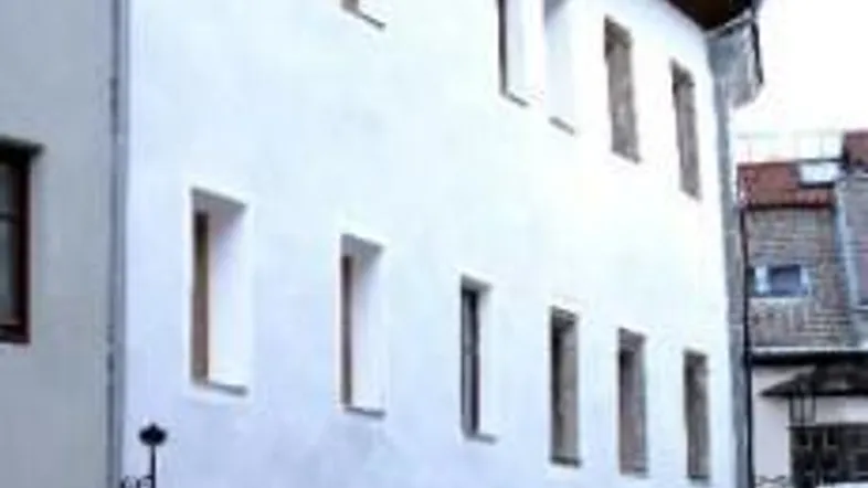 Historisches Gebäude mit weißer Fassade, mehreren Fenstern und charakteristischen Bogenöffnungen im Erdgeschoss.