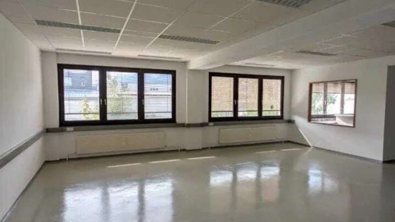 Geräumiges, leeres Büro mit vielen Fenstern, die für viel Tageslicht sorgen, und einem hellen Boden.