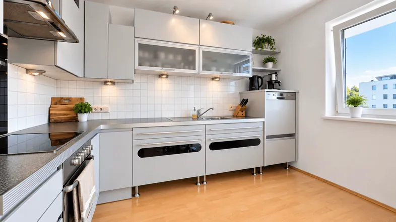 Helle, moderne Küche mit hellgrauen Schränken, integrierten Geräten und Fenster mit Ausblick.