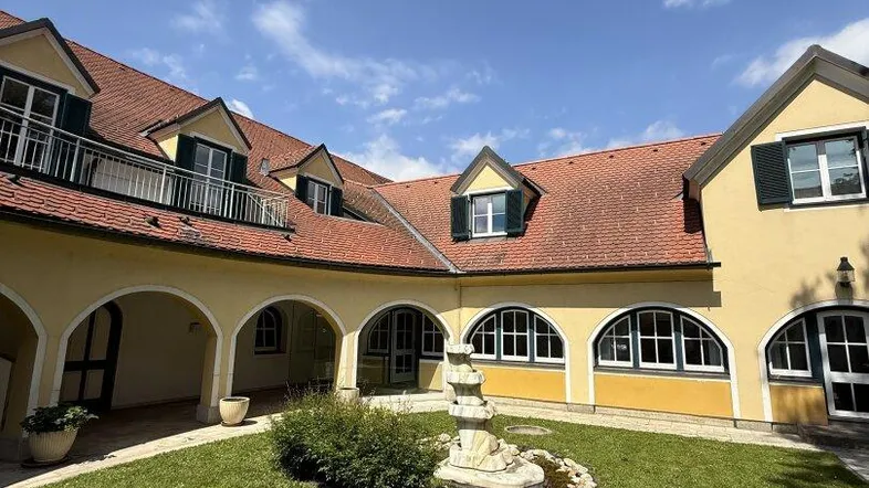 Malerischer Innenhof mit gepflegtem Rasen, einem Brunnen und traditioneller Architektur.