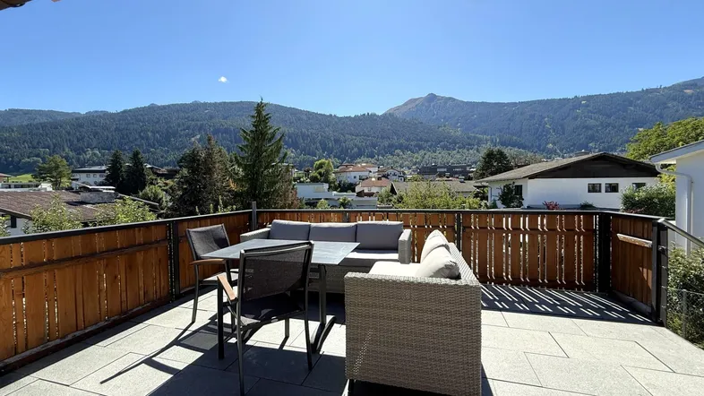 Geräumige Sonnenterrasse mit bequemen Gartenmöbeln und herrlichem Blick auf die umliegenden Berge.