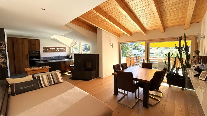 Helles, offenes Wohn-Esszimmer mit Holzbalkendecke, Kamin und Zugang zur Terrasse.