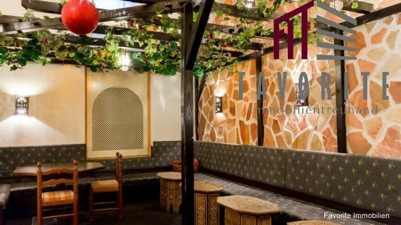 Thematisch gestalteter Innenbereich eines Restaurants mit Steinwand, Sitzbänken und dekorativen Pflanzen.