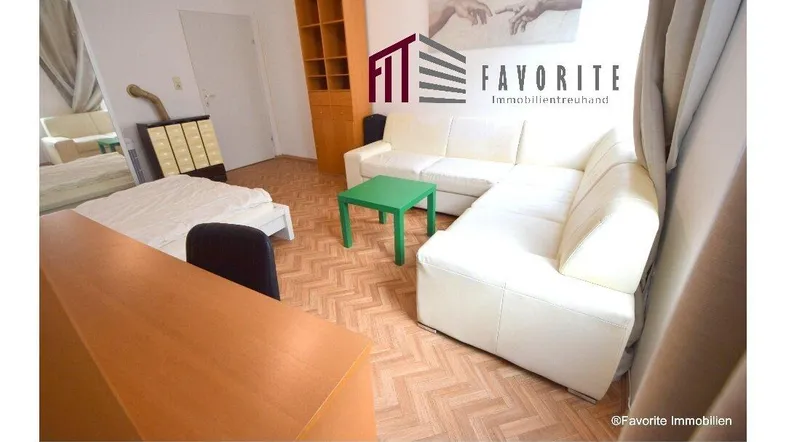 Heller Wohn- und Schlafbereich mit beigem Sofa, Bett und Parkettboden.