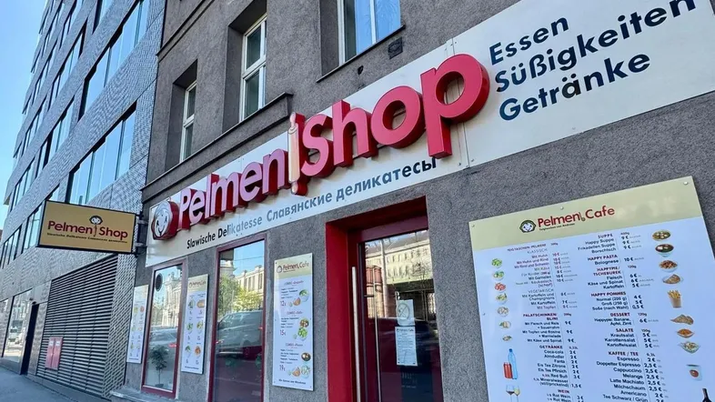 Außenansicht eines Geschäftsgebäudes mit rotem "Pelmenishop"-Schild und Informationen zu Speisen und Getränken.
