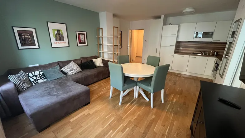 Offener Wohn-Essbereich mit integrierter Küche, Parkettboden und gemütlichem Sofa.