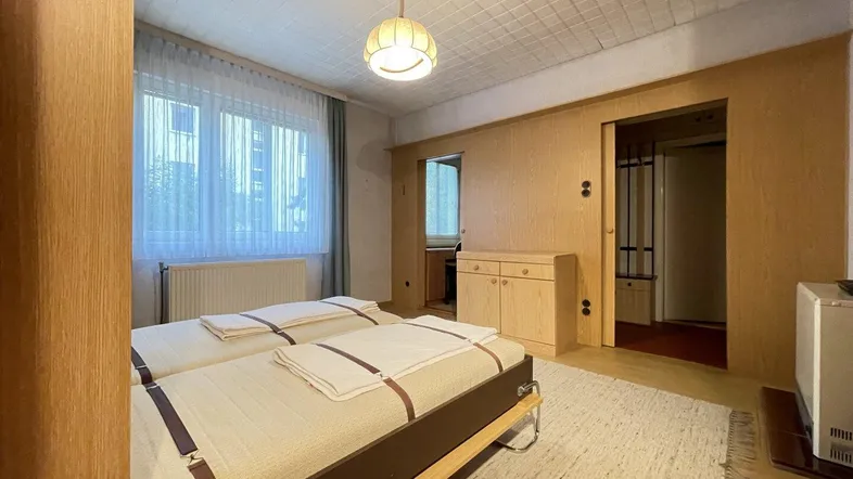 Schlafzimmer mit zwei Einzelbetten, Holzvertäfelung und Teppichboden.