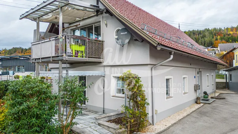 Traditionelles Haus mit rotem Ziegeldach und einem möblierten Balkon mit Überdachung.