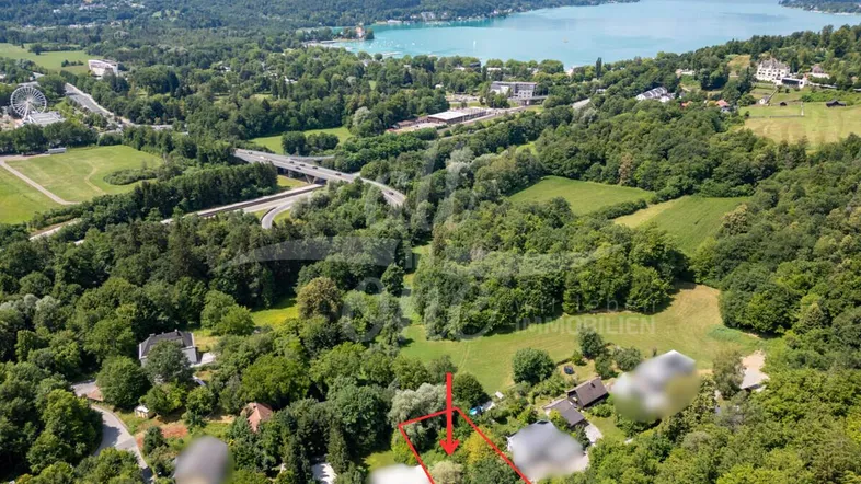 Luftaufnahme des Grundstücks mit See- und Bergblick, umgeben von viel Grün und Wald.